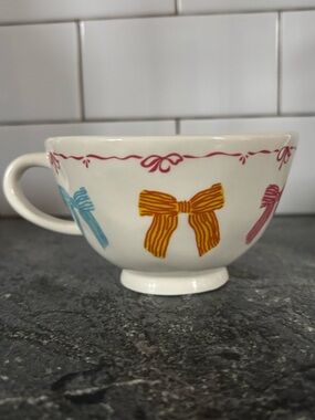 Urban Outfitters White Ceramic Teacup with Yellow, Blue, and Pink Bow Accents